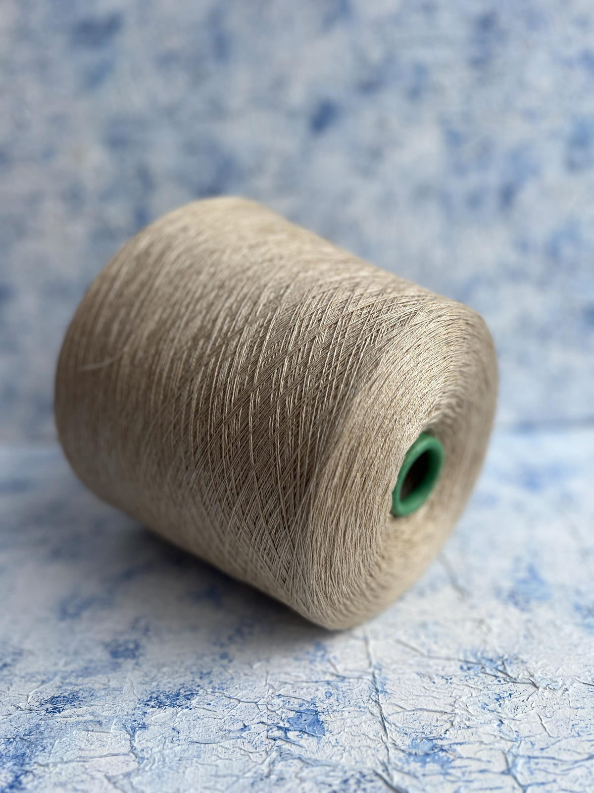 Close-up of a skein of fine, undyed lace weight yarn, showcasing its subtle sheen, delicate two-ply twist, and soft, ethereal halo.