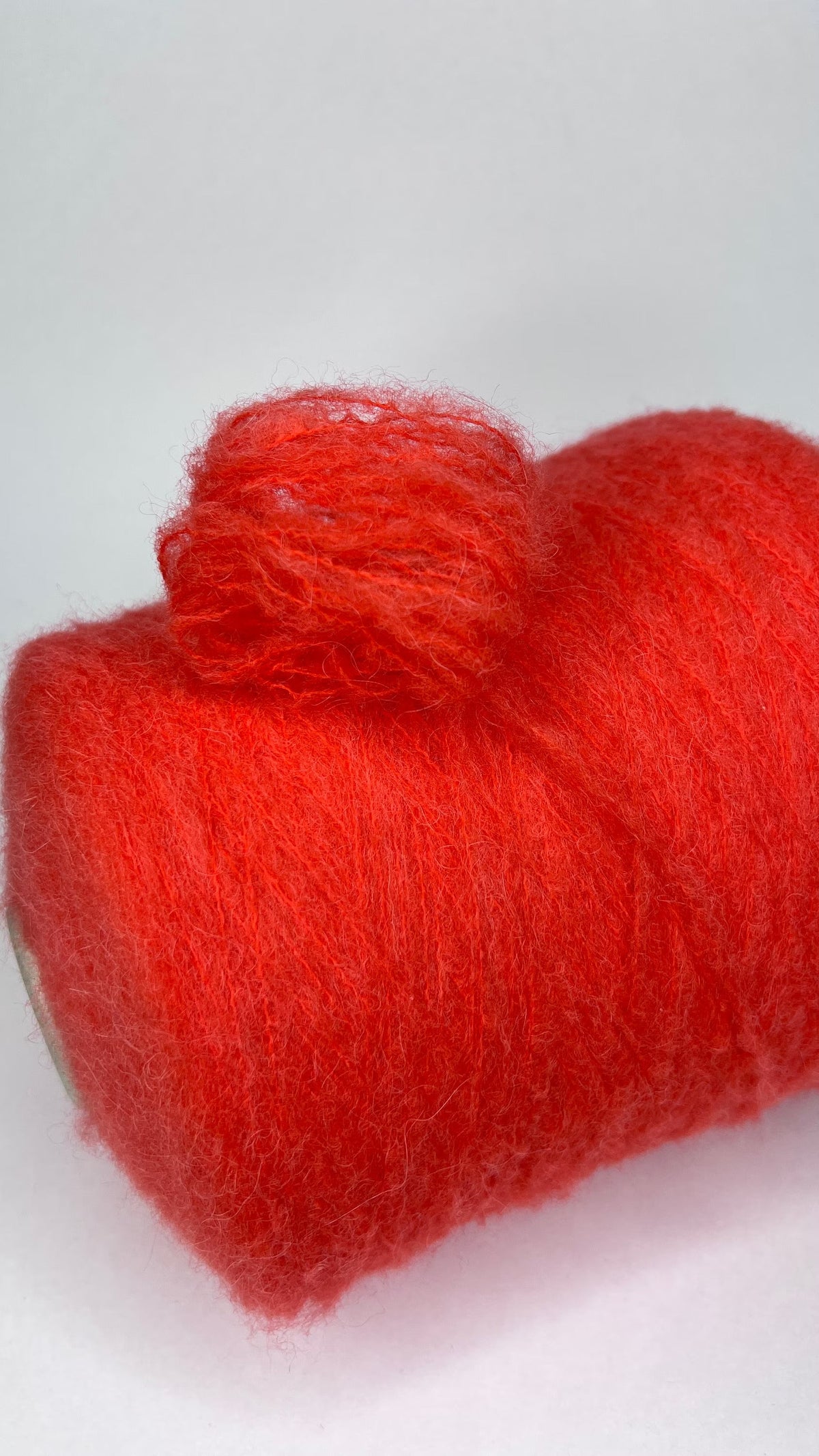 Luxurious orange yarn, soft with a subtle 'porridge' heathered texture. Features a delicate alpaca halo, gentle sheen, and a fine, even single-ply twist.