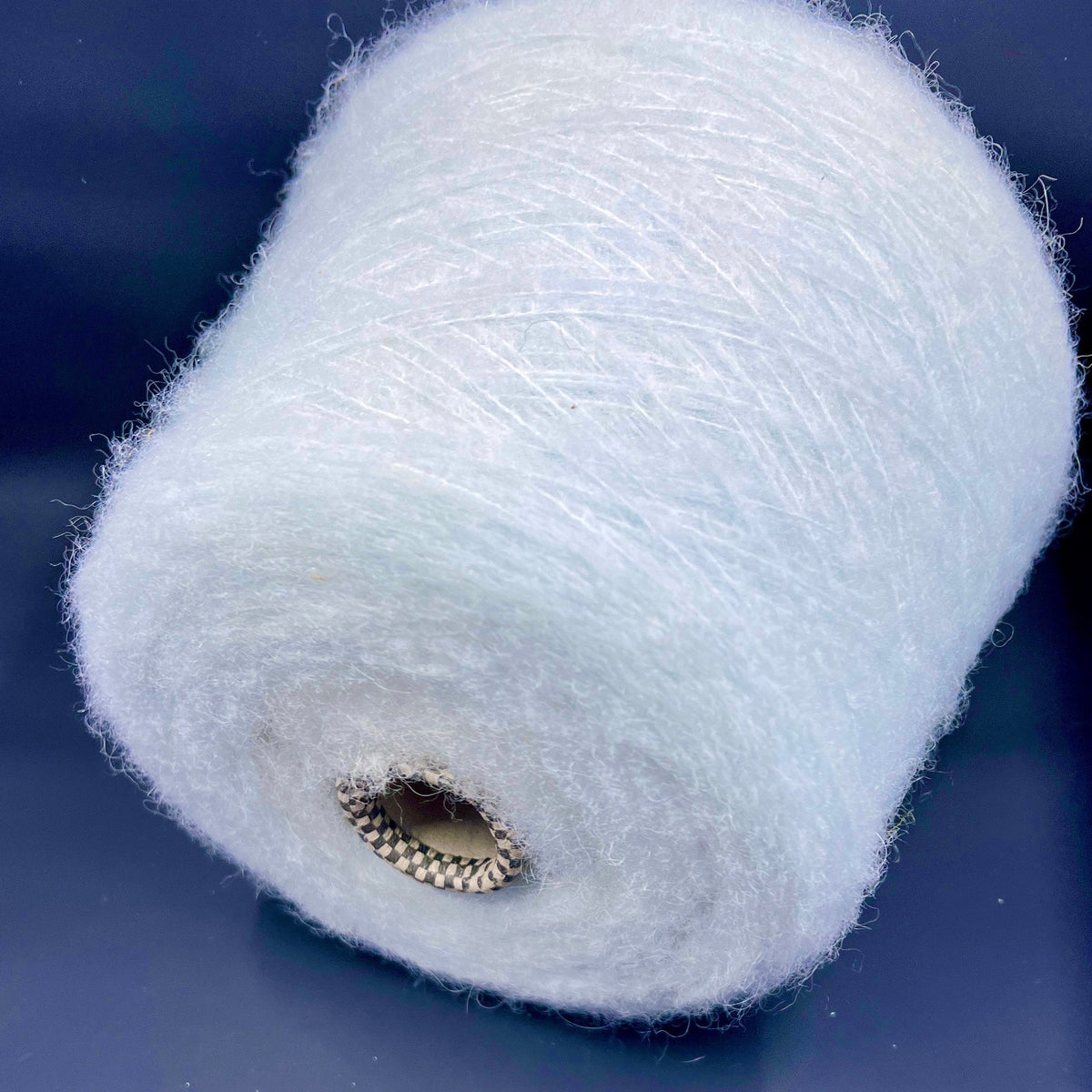 A delicate skein of pale mint green luxury yarn, exhibiting a fine, consistent twist, subtle sheen, and a soft, slightly fuzzy texture.
