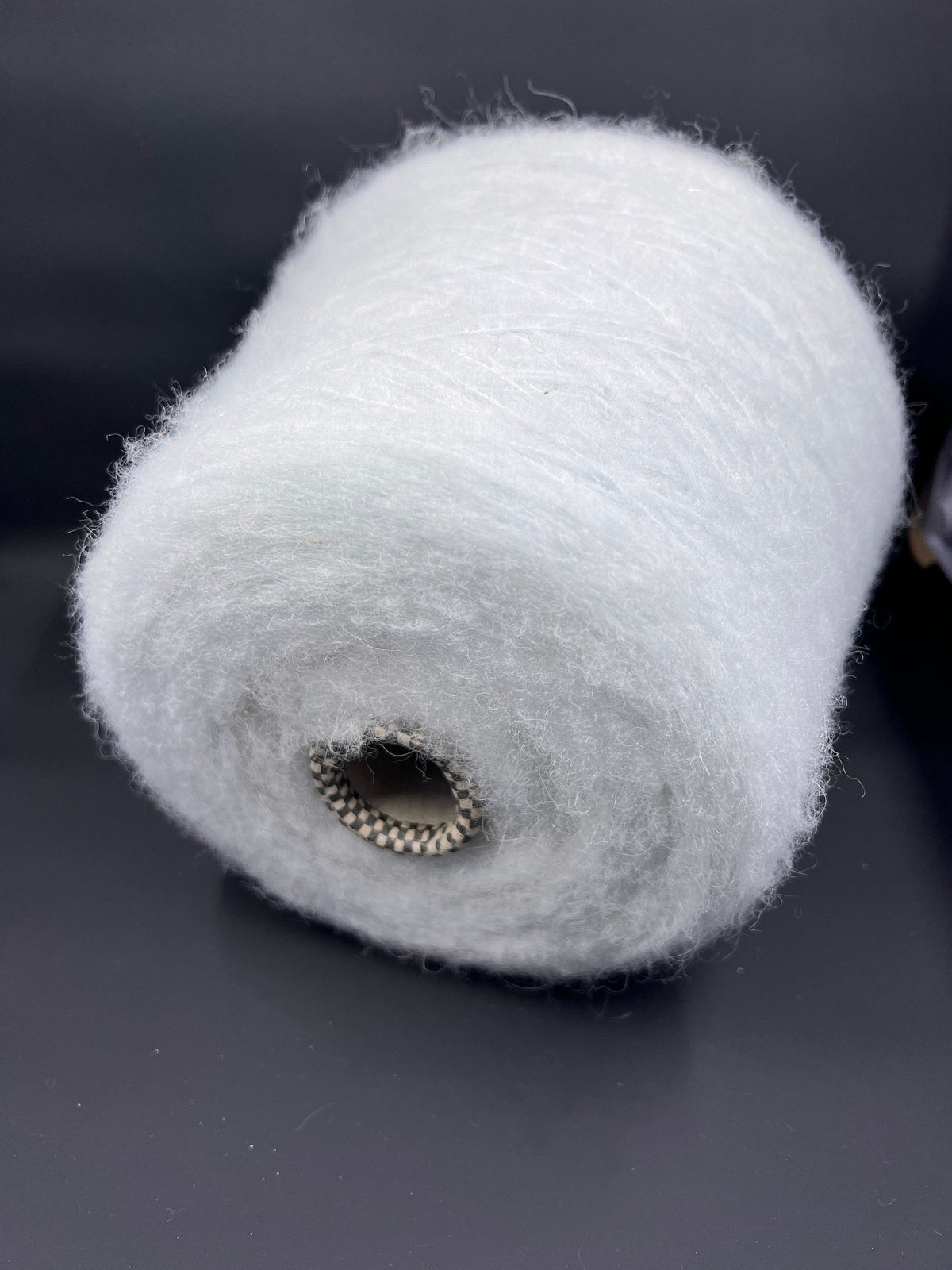 A delicate skein of pale mint green luxury yarn, exhibiting a fine, consistent twist, subtle sheen, and a soft, slightly fuzzy texture.