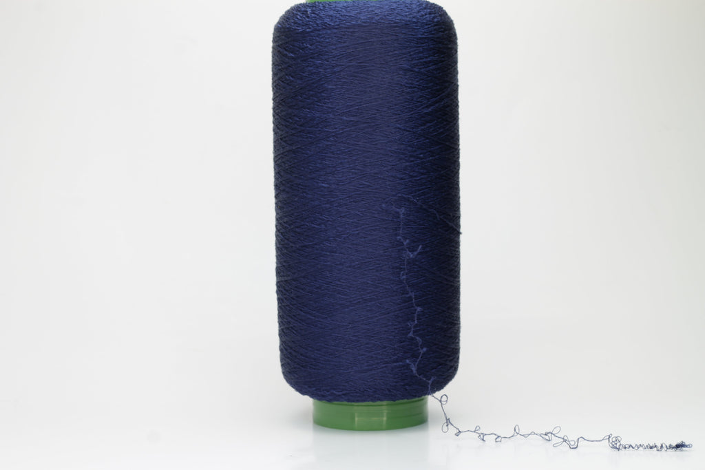 A tightly twisted, smooth two-ply thread of deep indigo blue, glistening with a high-luster sheen, wound onto a symmetrical cone.