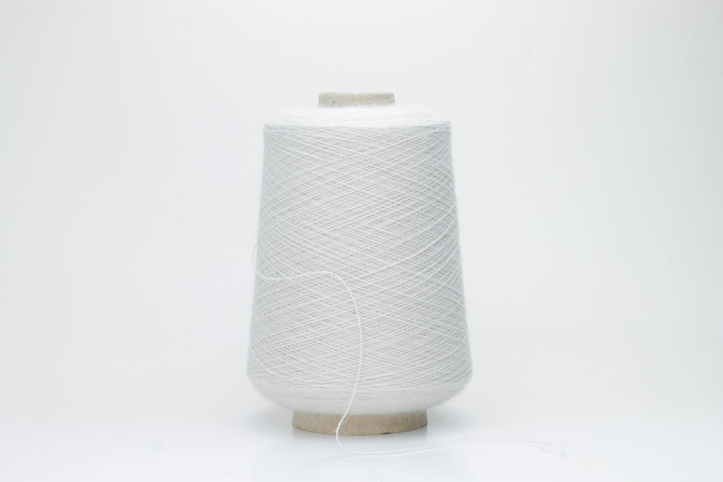 A close-up of soft, matte beige yarn, meticulously twisted into a fine 2-ply strand, showcasing its subtle fluffiness and consistent texture. The natural, warm hue is uniform throughout.