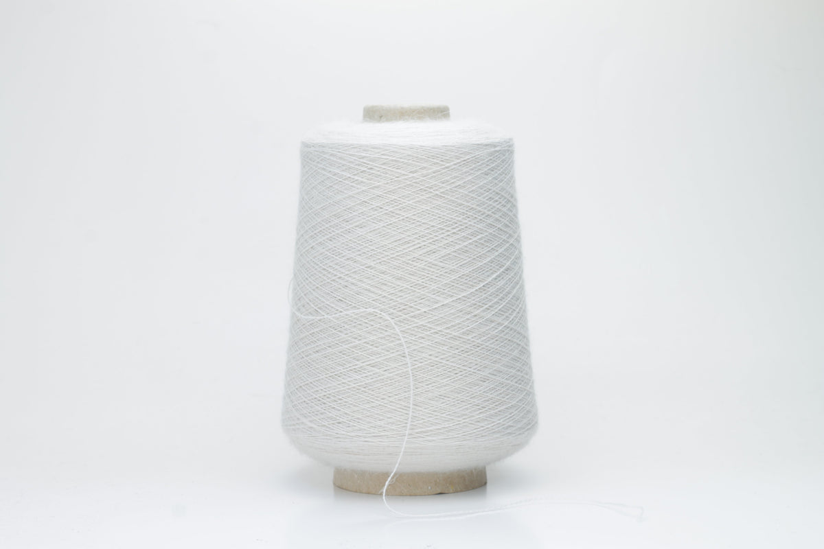 A close-up of soft, matte beige yarn, meticulously twisted into a fine 2-ply strand, showcasing its subtle fluffiness and consistent texture. The natural, warm hue is uniform throughout.
