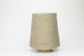 A skein of light beige yarn, showcasing a subtle sheen from the silk and a slight irregular texture from the linen fibers. The individual plies are gently twisted, creating a fluid, soft drape.