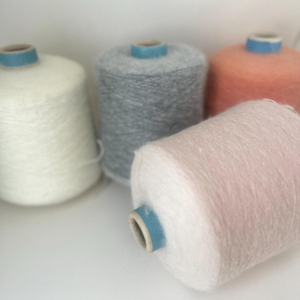 Finely spun, light gray yarn with a soft, visible fluffy halo. Ethereal, cloud-like texture and subtle sheen from premium alpaca fibers.