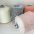 Finely spun, light gray yarn with a soft, visible fluffy halo. Ethereal, cloud-like texture and subtle sheen from premium alpaca fibers.