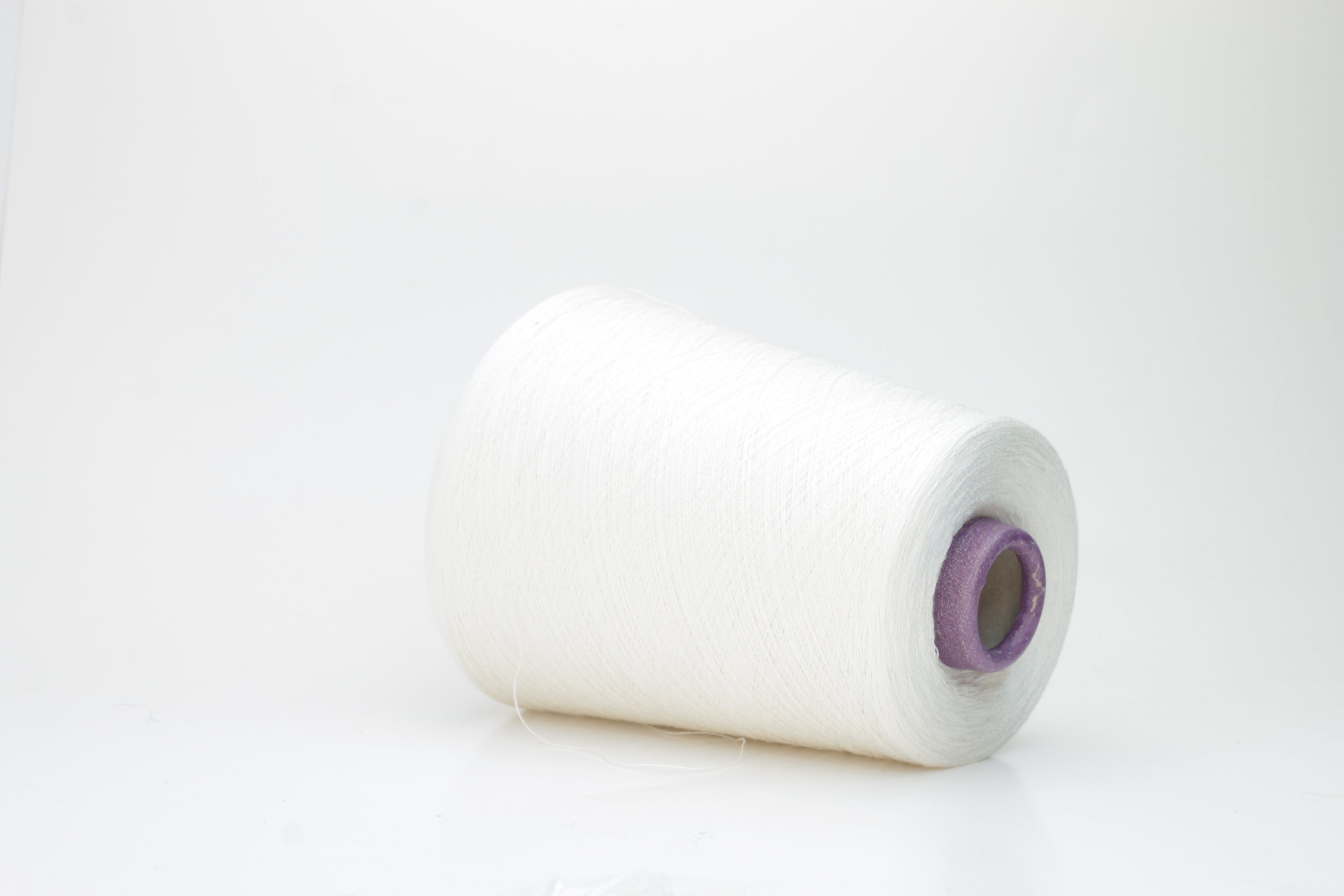 A meticulously spun, single-ply white yarn with a subtle sheen, gracefully coiled into a pristine hank, revealing its fine, smooth texture.