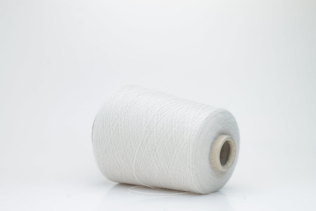 A close-up of soft, matte beige yarn, meticulously twisted into a fine 2-ply strand, showcasing its subtle fluffiness and consistent texture. The natural, warm hue is uniform throughout.