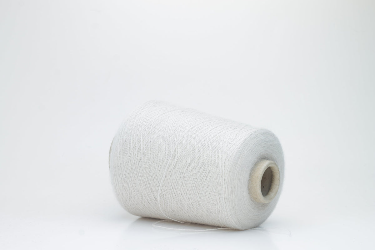 A close-up of soft, matte beige yarn, meticulously twisted into a fine 2-ply strand, showcasing its subtle fluffiness and consistent texture. The natural, warm hue is uniform throughout.