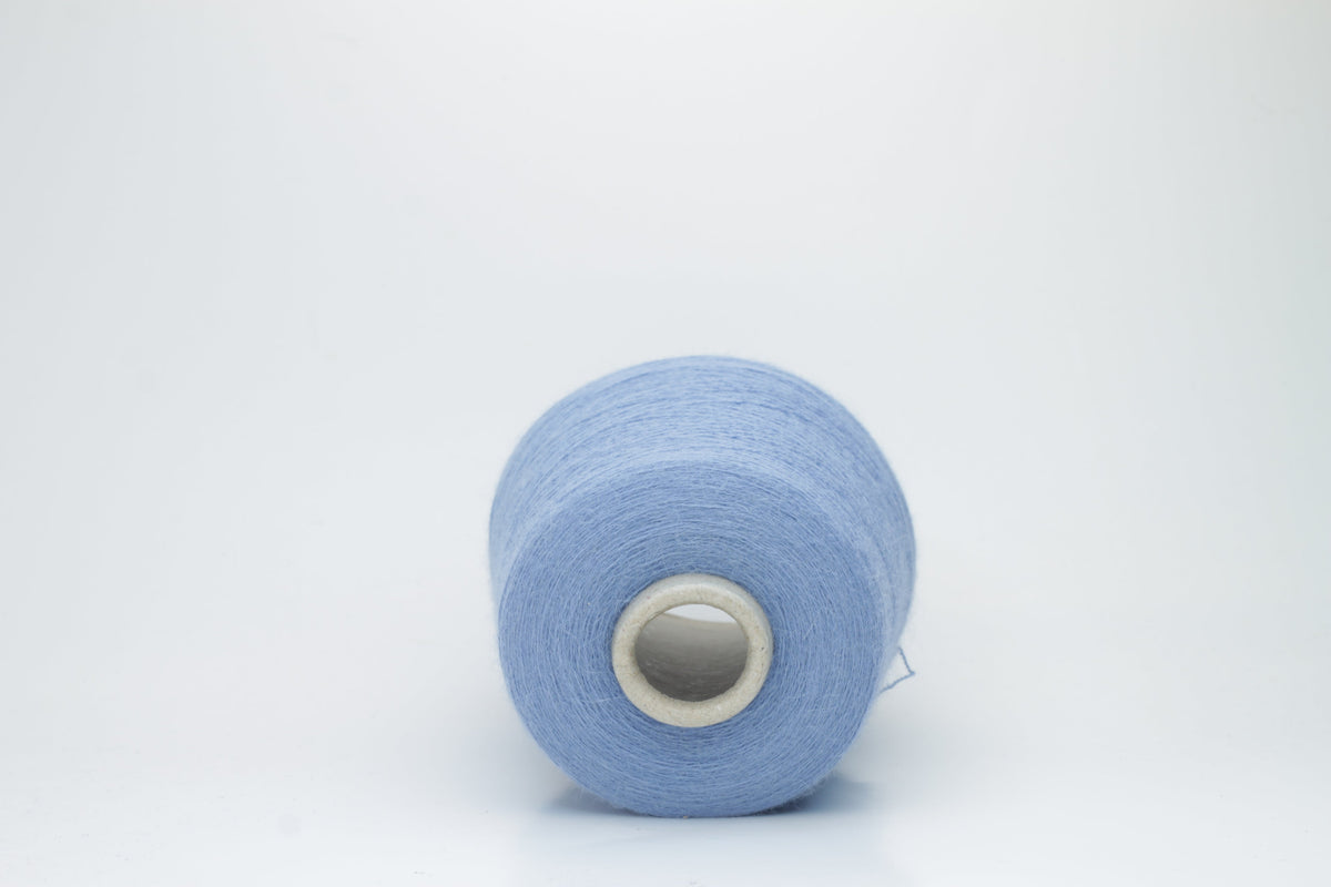 Close-up of a skein of soft, slightly fuzzy two-ply yarn in a deep, vibrant cerulean blue with a subtle, natural sheen.