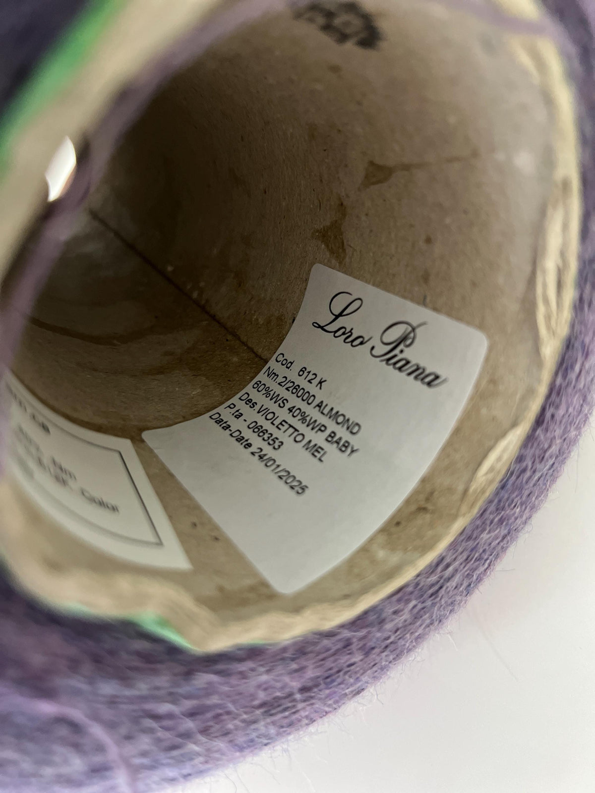 A lustrous skein of deep, rich violet yarn, visibly soft and fluffy with a delicate halo. The fibers show a subtle, luxurious sheen.