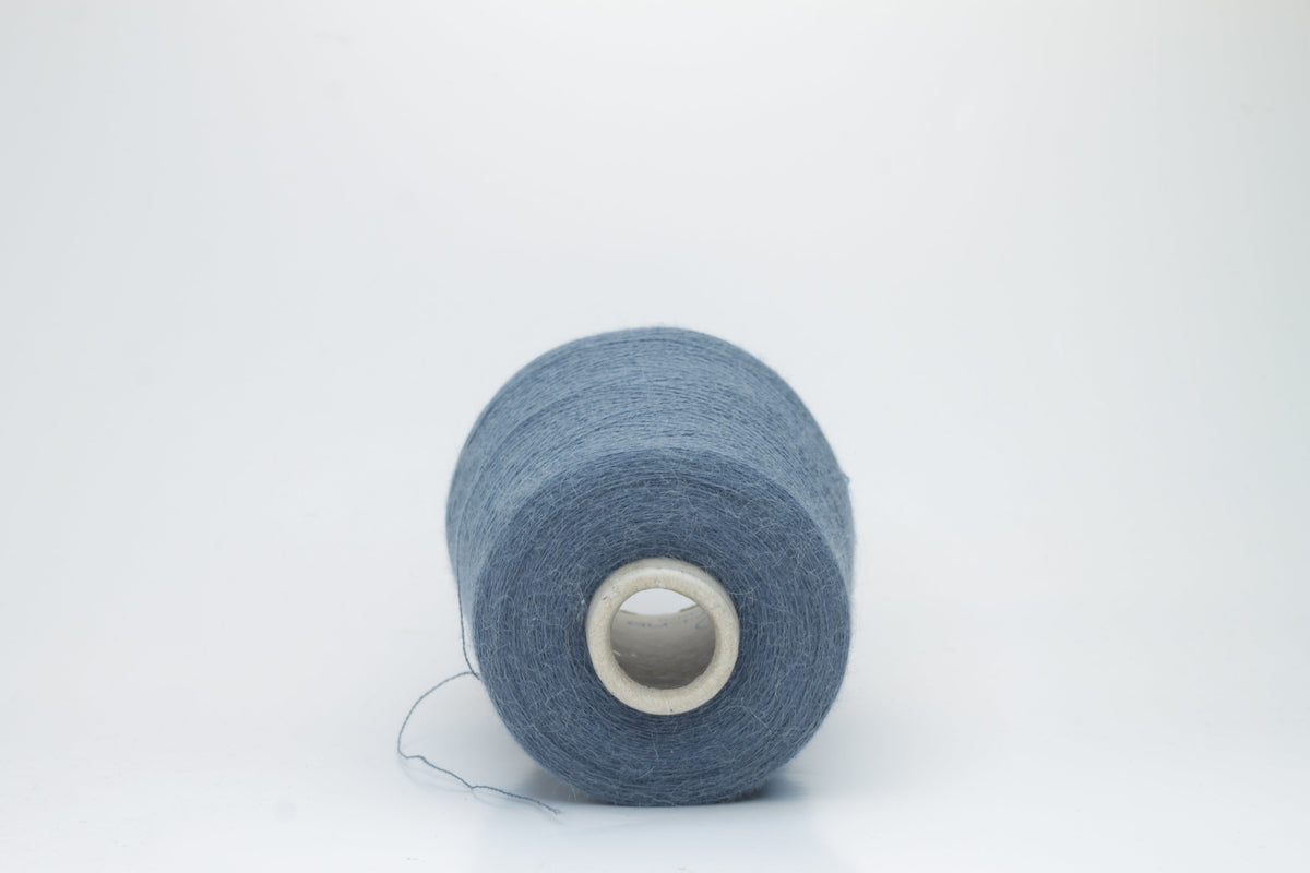 A skein of deeply saturated cerulean blue yarn, visibly soft with a subtle, plush halo. Features a fine, consistent two-ply twist structure.