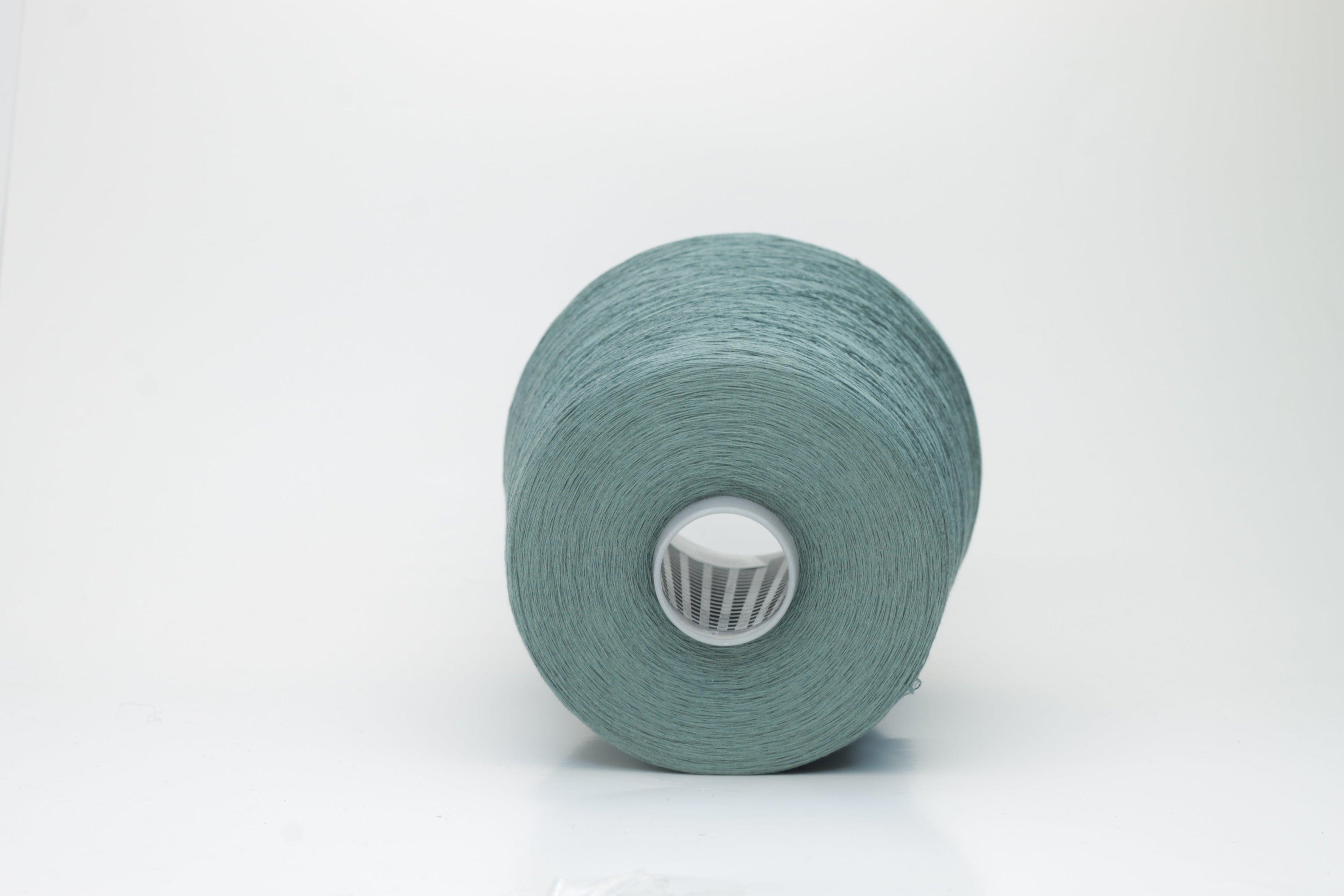 A finely spun skein of vibrant green silk cotton yarn with a subtle, natural sheen. The tight, smooth twist of the fibers is visible.