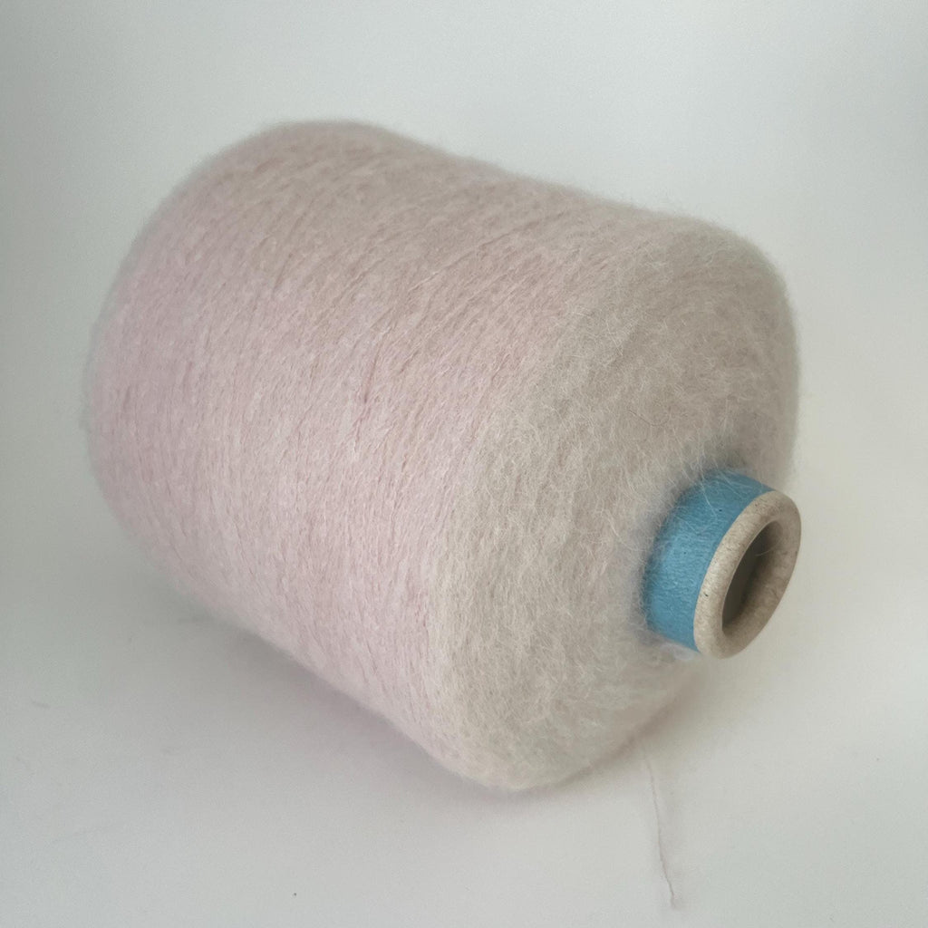 Close-up of a generous skein of extremely fine, very fluffy light pink yarn, showing a soft, airy halo and subtle, even twist throughout the thread.