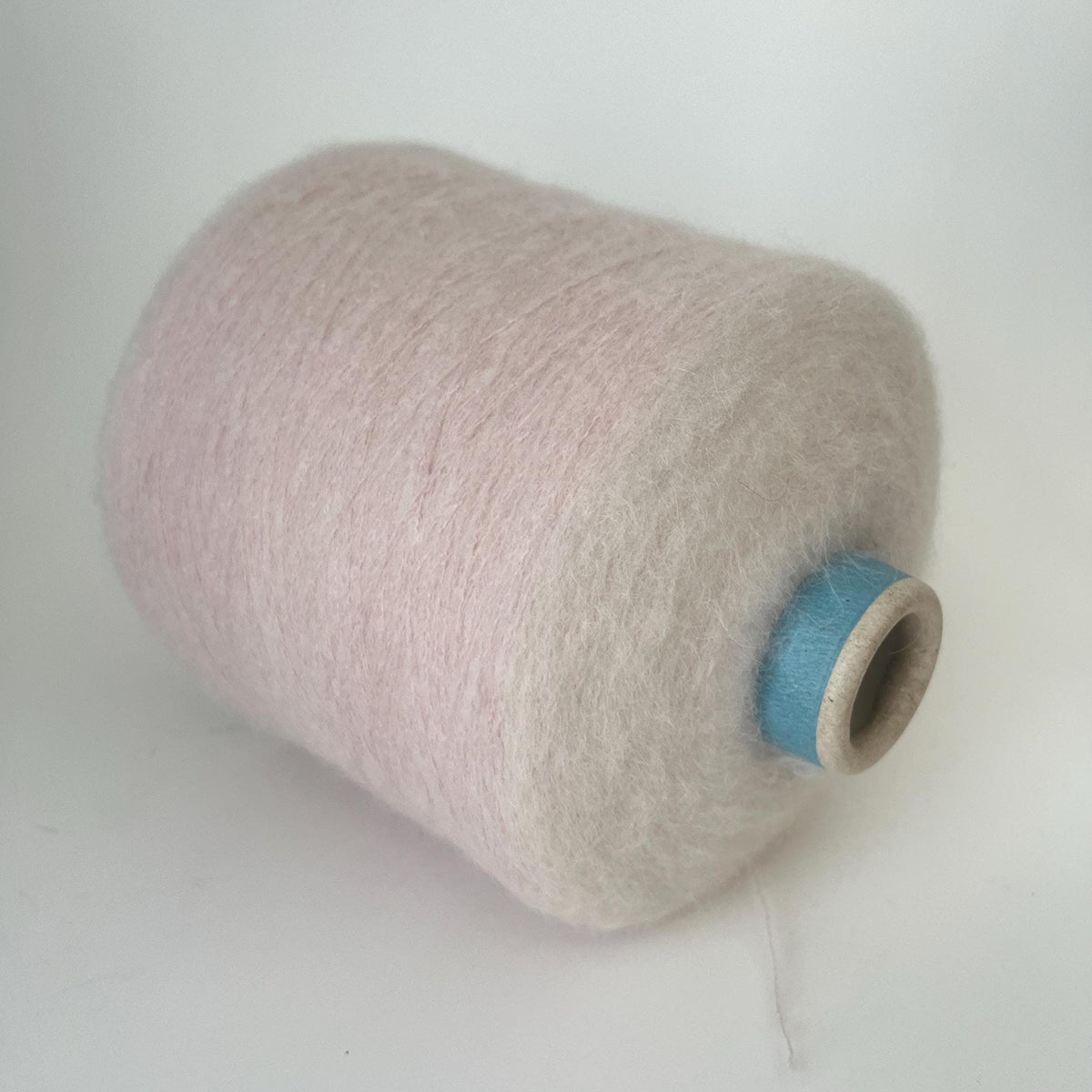 Close-up of a generous skein of extremely fine, very fluffy light pink yarn, showing a soft, airy halo and subtle, even twist throughout the thread.