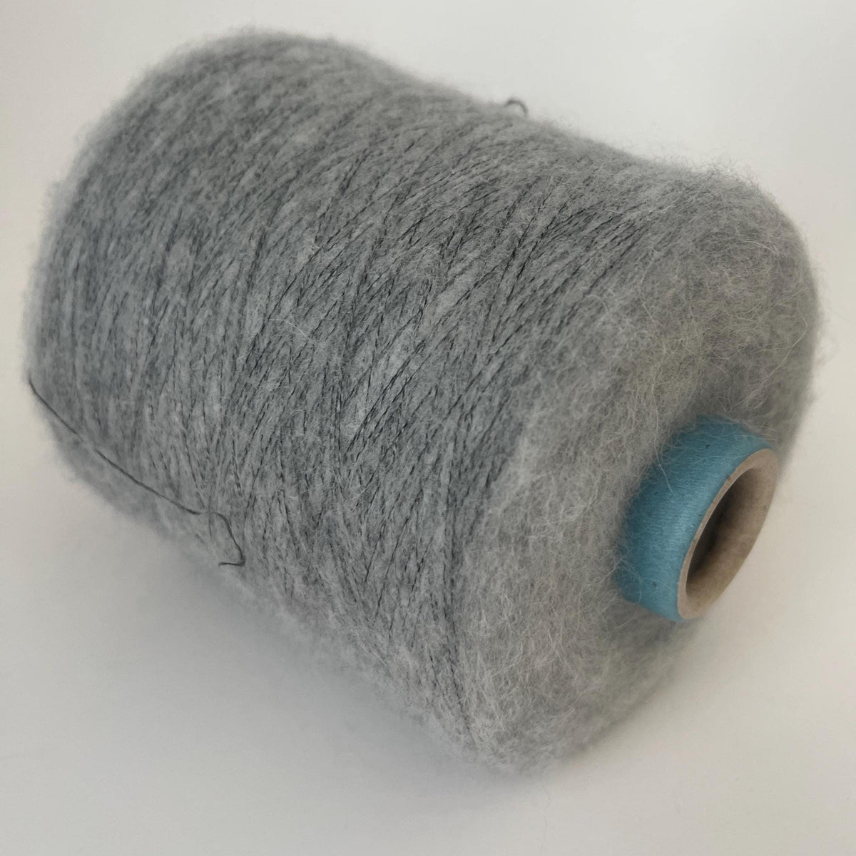 Finely spun, light gray yarn with a soft, visible fluffy halo. Ethereal, cloud-like texture and subtle sheen from premium alpaca fibers.